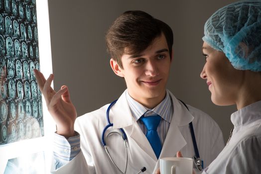 medical colleagues confer near the x-ray image fixed on the glowing screen