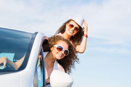 young attractive woman in sunglasses got out of the car window and laugh