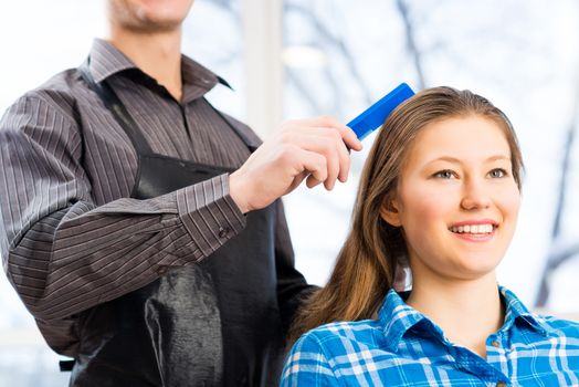 male hairdresser puts woman's hair in a hairdressing salon