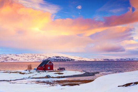 Norway in winter: mountains with colorful houses and the ocean at sunset.