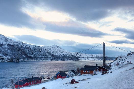 Norway in winter: mountains with colorful houses and the ocean at sunset.
