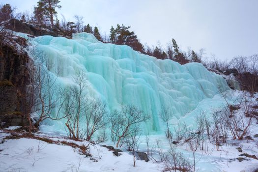 Blue ice and icicles at a frozen waterfall in Norway