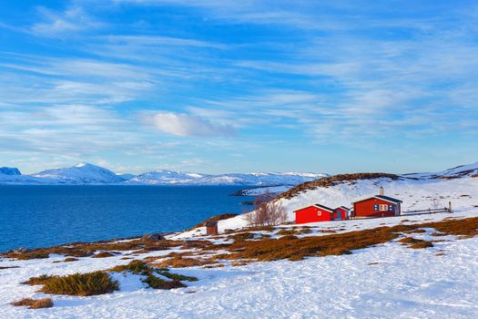 Norway in winter: mountains with colorful houses and the ocean on a sunny winter day.