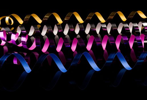 Colorful, curly  streamers with reflectin on black background