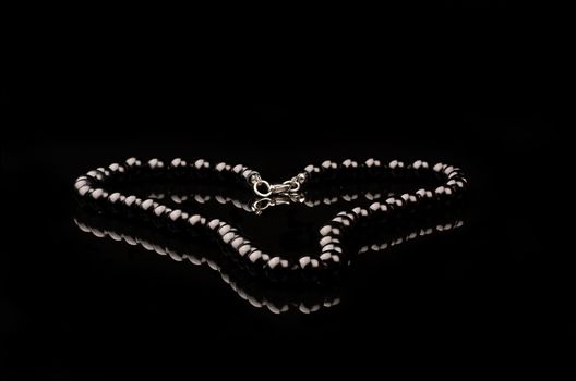 black peral necklace with refelction on black backgrounf