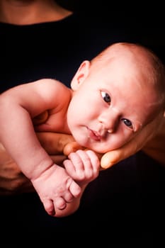 Newborn baby on the father's hands on black