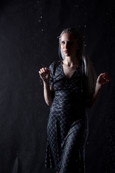 girl in grey dress in the rain on black background 

