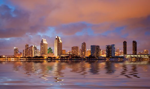 Skyline cityscape of San Diego downtown skyscrapers at night with lights reflecting into the ocean