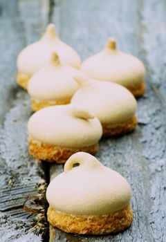 Arrangement of Swirled Meringue Topping with Biscuit Bottom isolated on Grey Wooden background