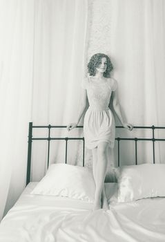 Attractive cute girl in the bedroom on the bed in vintage dress