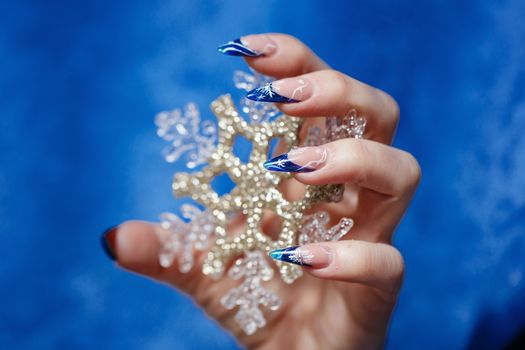 Female hand with beautiful manicure holding a snowflake shot closeup