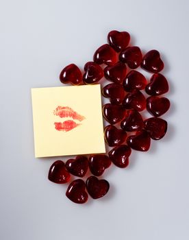 Imprint of female lips with red lipstick on a sticker surrounded by hearts from glass