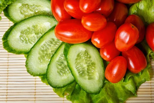 Ripe cherry tomatoes, cucumbers and lettuce closeup shot