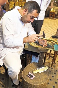 FES, MOROCCO - OCTOBER 17, 2013: Man making antique arab handicrafts on a golden plate