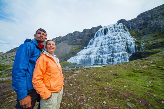 Couple of tourists near Dynjandi is the most famous and beautiful waterfall of the West Fjords in Iceland.