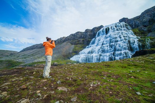 Young woman photographed Dynjandi is the most famous and beautiful waterfall of the West Fjords in Iceland.