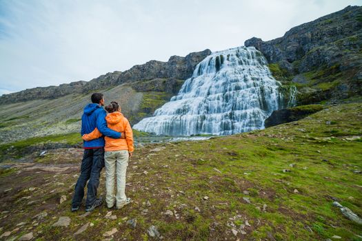 Couple of tourists near Dynjandi is the most famous and beautiful waterfall of the West Fjords in Iceland.