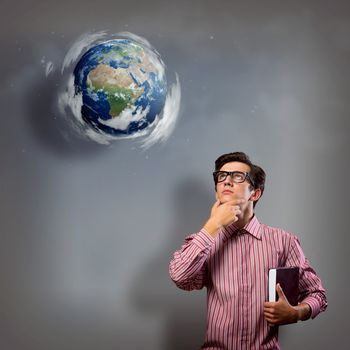 young man with a book thinks. it over planet Earth with clouds. an image of NASA.