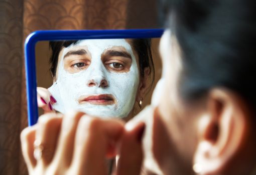 young beautiful woman takes beauty mask in front of mirror