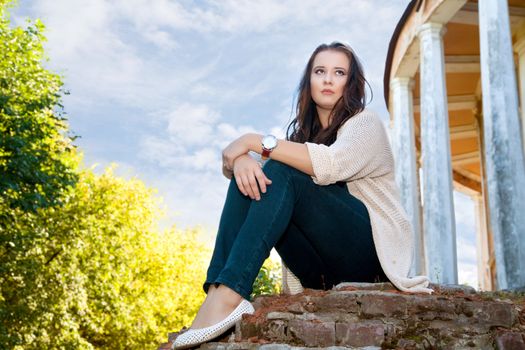  plus size girl sits on an old brick wall in the summer evening