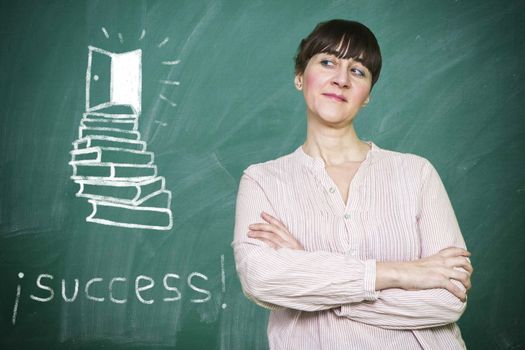Woman smiles writes on a blackboard the concept of success