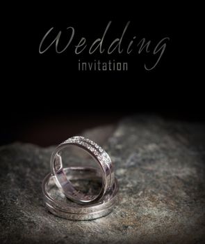 Two silver rings on rock - wedding invitation