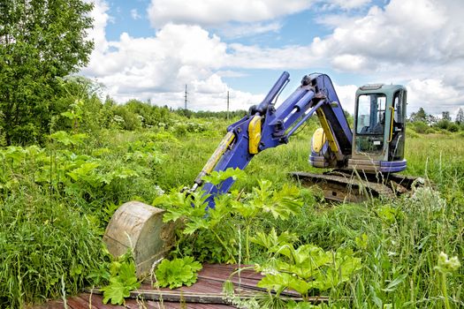 Caterpillar dredge in the field among a grass