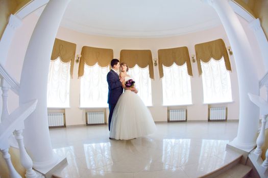 groom and bride in hall with staircase