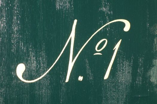 White number one written in italic with abbreviation No. and digit one against dark green weathered wooden background