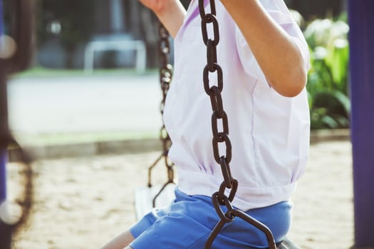 Little child on a swing in the park.