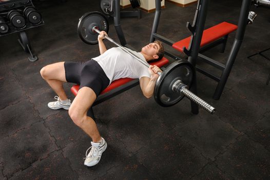 handsome young man doing bench press workout in gym