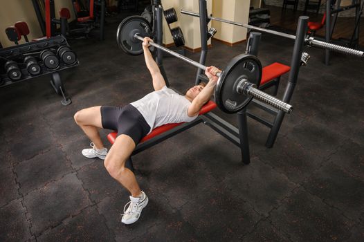 handsome young man doing bench press workout in gym
