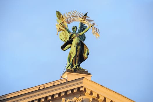 Statue at the roof of theater in Lviv, Ukraine, in rays of sunset.