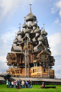 Wooden Church of Transfiguration at Kizhi island in Russia under reconstruction. Excursion group listening to the guide.