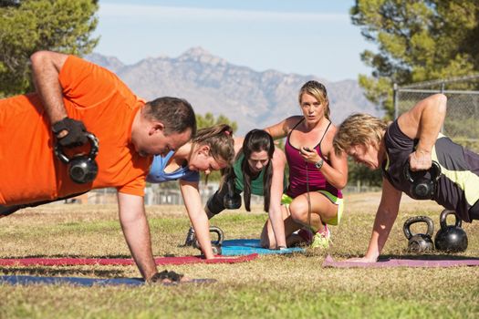 Young woman working with adults in boot camp fitness class