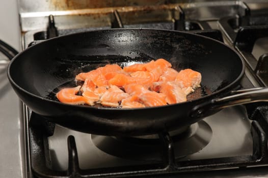 pieces of red fish frying on oil in the pan