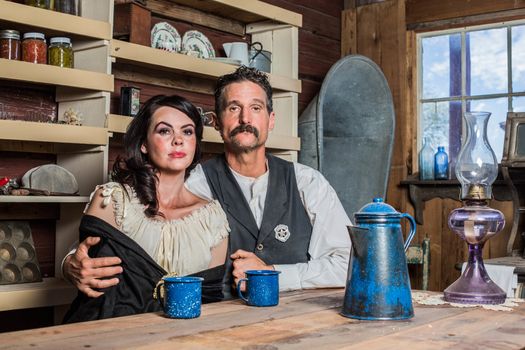 Western sheriff poses with a woman for a portrait inside a house