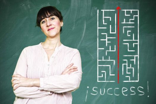 Woman smiles writes on a blackboard to learn concept