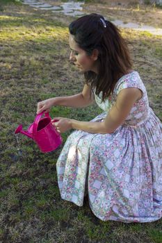 Woman watering green garden. Mature girl gardening in her backyard. spring season, rural scene