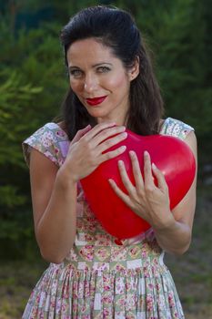 Valentine's Day. Beautiful smiling woman with a gift in the form of heart in his hands