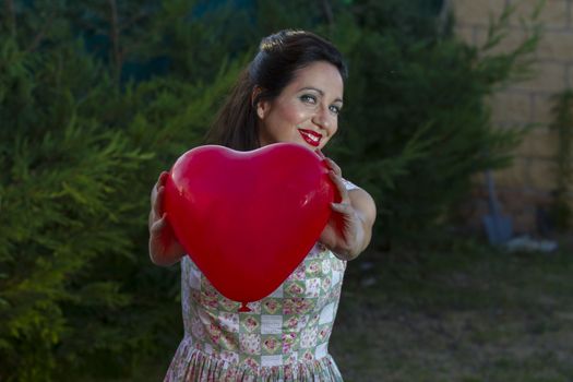 Valentine's Day. Beautiful smiling woman with a gift in the form of heart in his hands