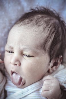 new born baby curled up sleeping on a blanket, multiple expressions