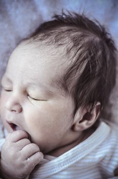 new born baby curled up sleeping on a blanket, multiple expressions