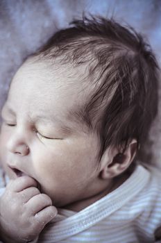 new born baby curled up sleeping on a blanket, multiple expressions