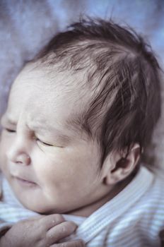 new born baby curled up sleeping on a blanket, multiple expressions