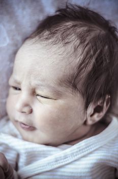 new born baby curled up sleeping on a blanket, multiple expressions