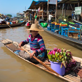 INLE LAKE, MYANMAR - 07 JAN 2014: Floating vendor on small  long wooden boat row to sell fresh lotus flowers to tourists
