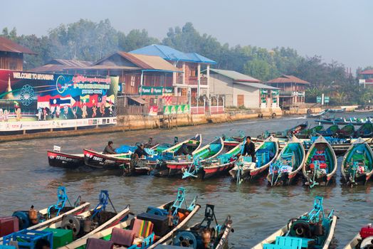 NYAUNG SHWE, INLE LAKE, MYANMAR (Burma) - 07 JAN 2014: Many long wooden tourist boats wait for customers at moorages. Most transportation on the lake is traditionally by boats.