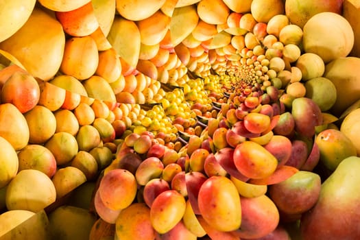 Repeating pattern of a pile of ripe mangos on a fruit stand