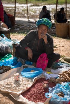 INLE LAKE, MYANMAR (BURMA) - 07 JAN 2014: Local Burmese Intha woman smoke cheroot cigar and sell  on a traditional open market. Local markets serves most common shopping needs Inle Lake people.